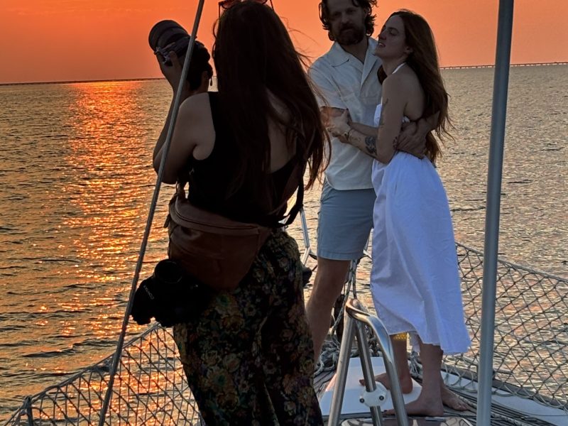 People on a boat at sunset, with a couple posing for a photo.