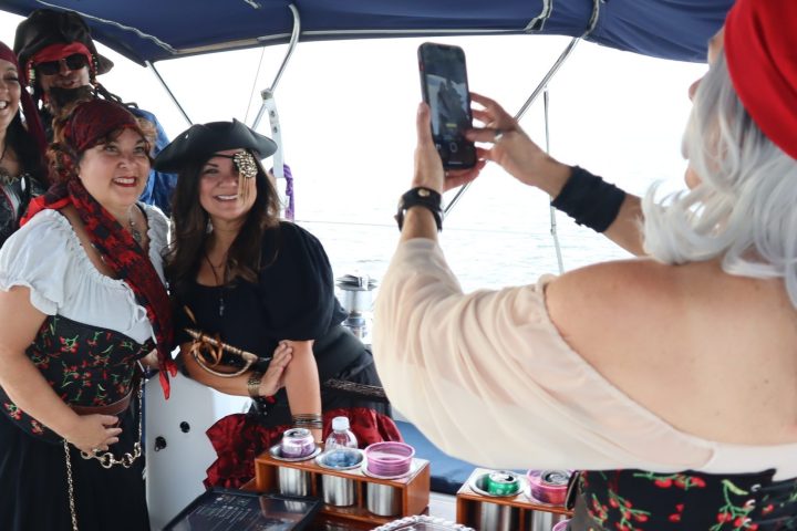 Four people in pirate costumes pose for a photo on a boat.