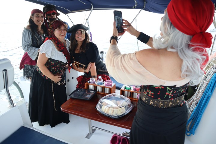 Four people in pirate costumes pose for a photo on a boat.