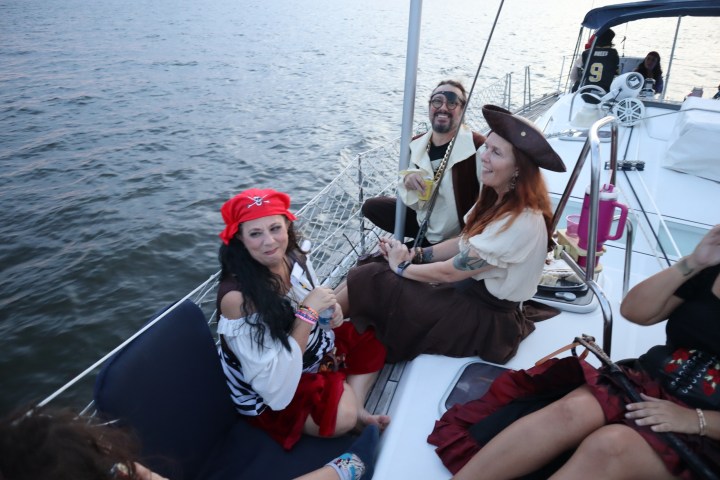 People in pirate costumes enjoy a boat ride on the water.