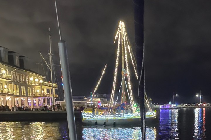 A boat decorated with lights on the water near a lit-up building at night.
