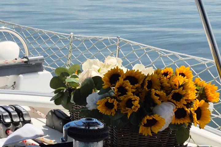 Sunflowers in a basket on a boat, with calm sea and blue sky in the background.